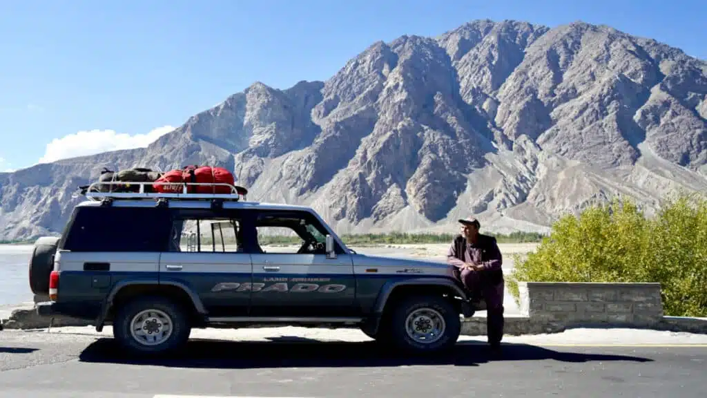 A rugged off-road vehicle parked agains a stunning mountain backdrop - B4Experience
