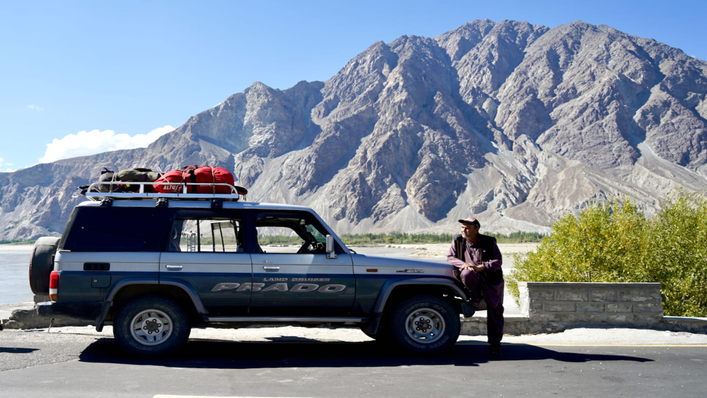 A rugged off-road vehicle parked agains a stunning mountain backdrop - B4Experience