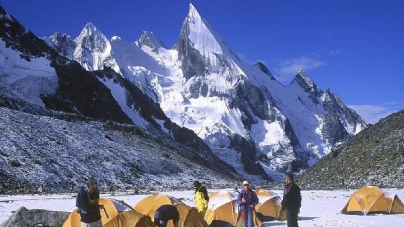 Yellow tents stand beneath snowy peaks in Trek K2 Laila Peak - B4Experience