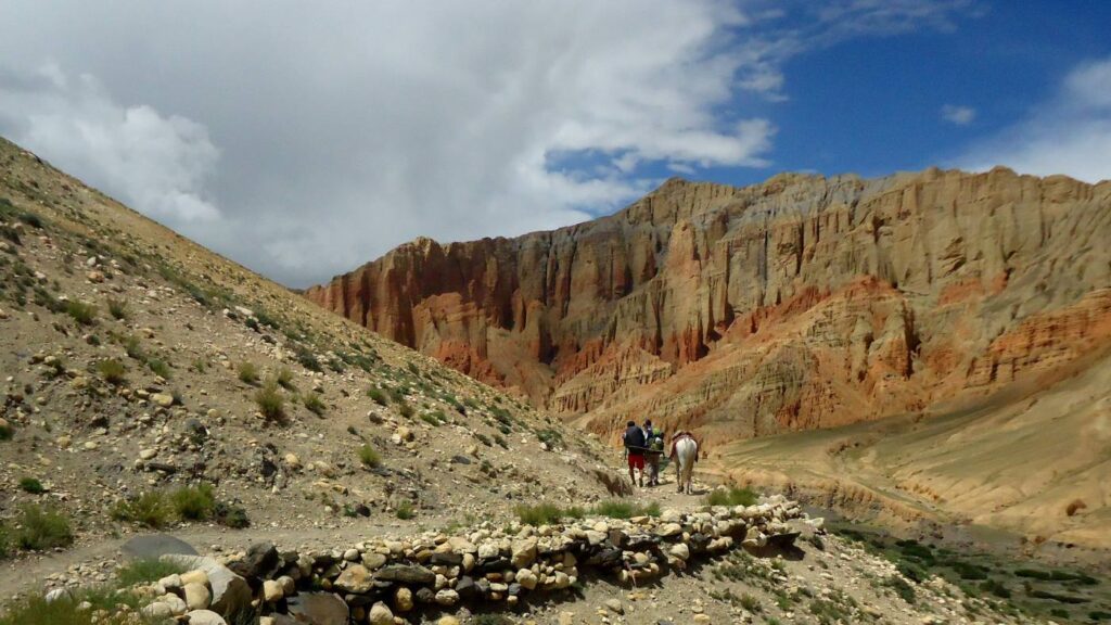 Group of trekking exploring the striking red cliffs of Mustang Dhakmar - B4Experience