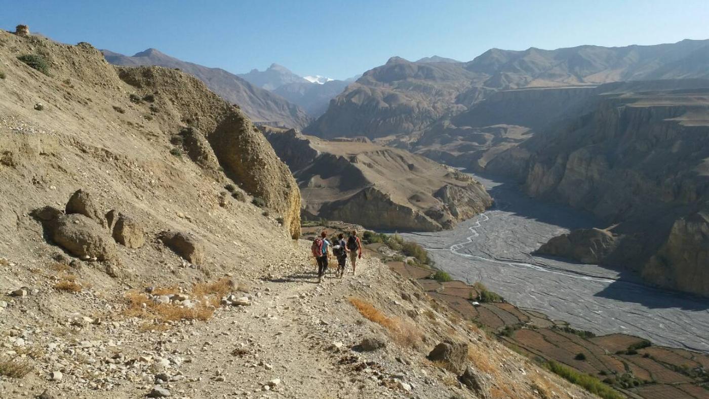 Hikers on a scenic trail above a winding river in Upper Mustang - B4Experience