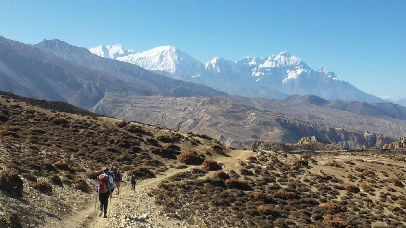 Hikers trekking through Upper Mustang with a backdrop of snow-capped mountains - B4Experience