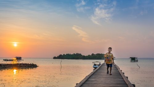 Child walking on a pier at sunset in the Solomon Islands - B4Experience